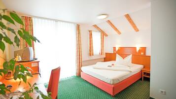 A hotel room with a bed, desk, chair, and a window with curtains.