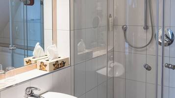 A modern bathroom with a glass-enclosed shower, a white sink, and a mirror above the sink.