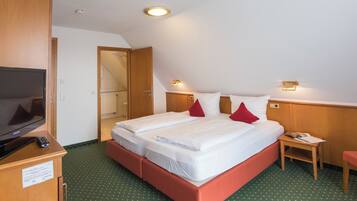 A hotel room with a large bed, a TV, a desk, and a chair.