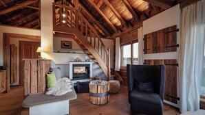A cozy living room with a fireplace, wooden furniture, and a staircase leading to an upper level.