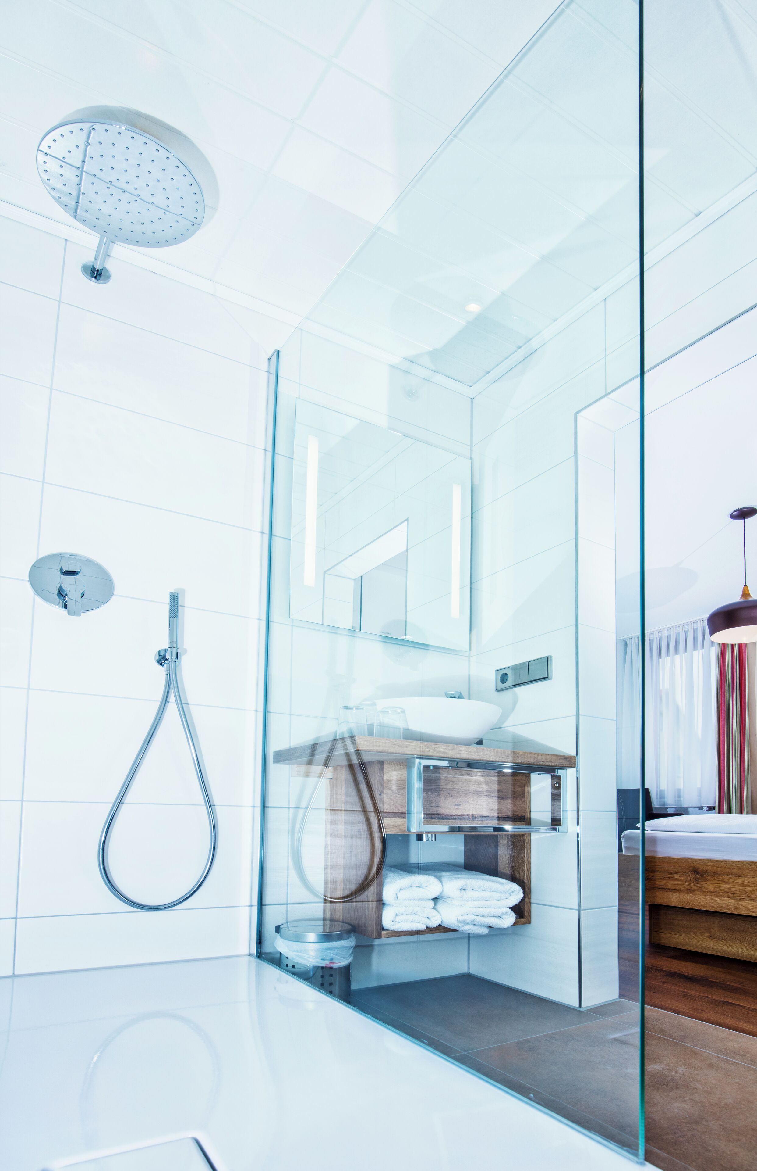 Un baño moderno con cabina de ducha de vidrio, lavamanos a la vista y un espejo.