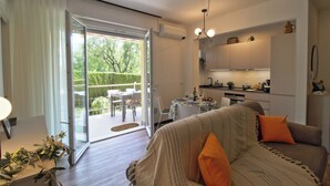 A modern living room with a sofa, a dining table, and a kitchen area.