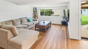 Een moderne woonkamer met een beige modulaire bank, een houten salontafel en een aan de muur bevestigde televisie.