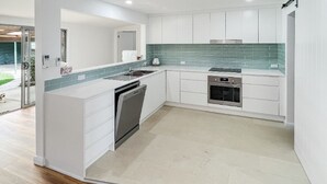 Een moderne keuken met witte kastjes, een groene betegelde spatwand en een ingebouwde oven.