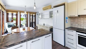 A modern kitchen with a marble countertop, white cabinetry, a built-in oven, and a refrigerator. - Junior Villa AA02 - Zeus (Kouklia)