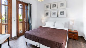 A bedroom with a bed, bedside tables, and a window with curtains. - Junior Villa AA02 - Zeus (Kouklia)
