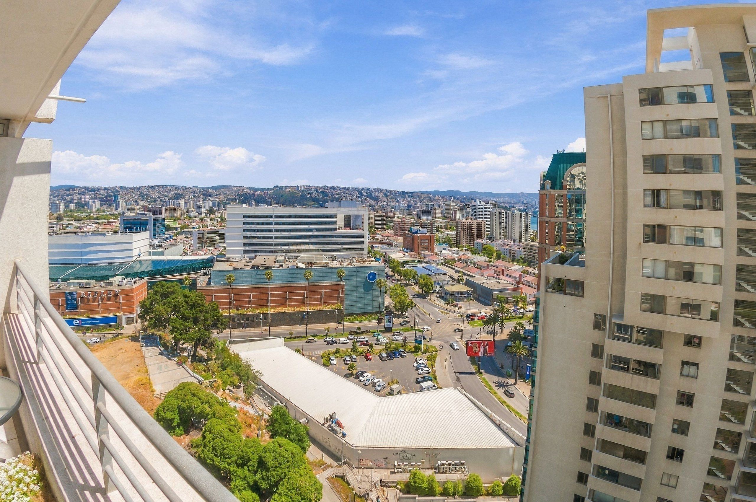Paisagem urbana com edifícios modernos, um estádio e uma área de estacionamento.
