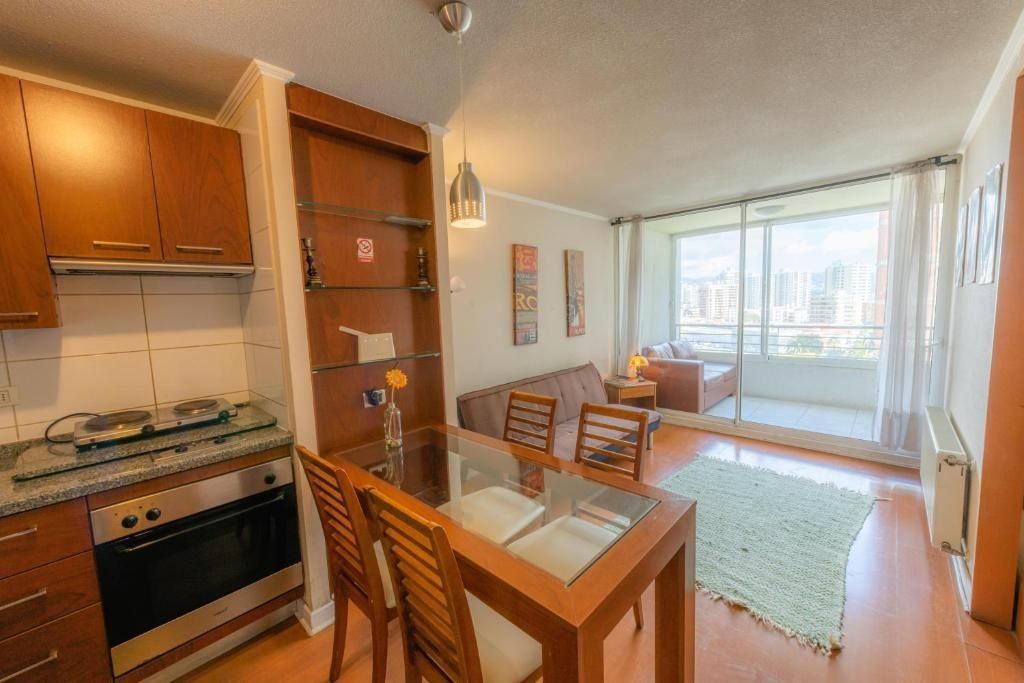 A modern kitchen with a dining area, a large window with a city view, and a cozy seating area.