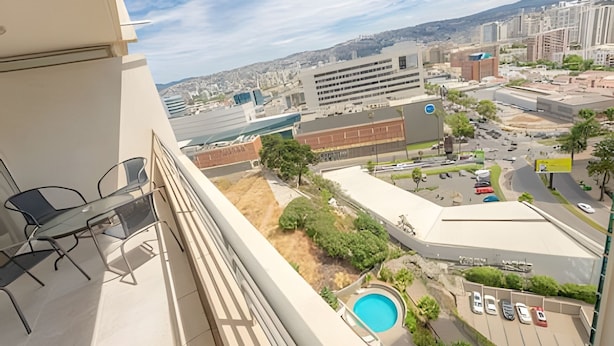 Ein Balkon mit Pool, Blick auf eine Stadtlandschaft und ein Parkbereich.