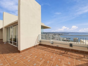 A balcony with a view of a body of water and distant cityscape.