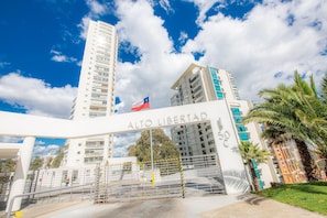 A modern building with 'ALTO LIBERTAD' signage, a flag, and a gated entrance. - Oceana Suites Alto Libertad (Vina del Mar)