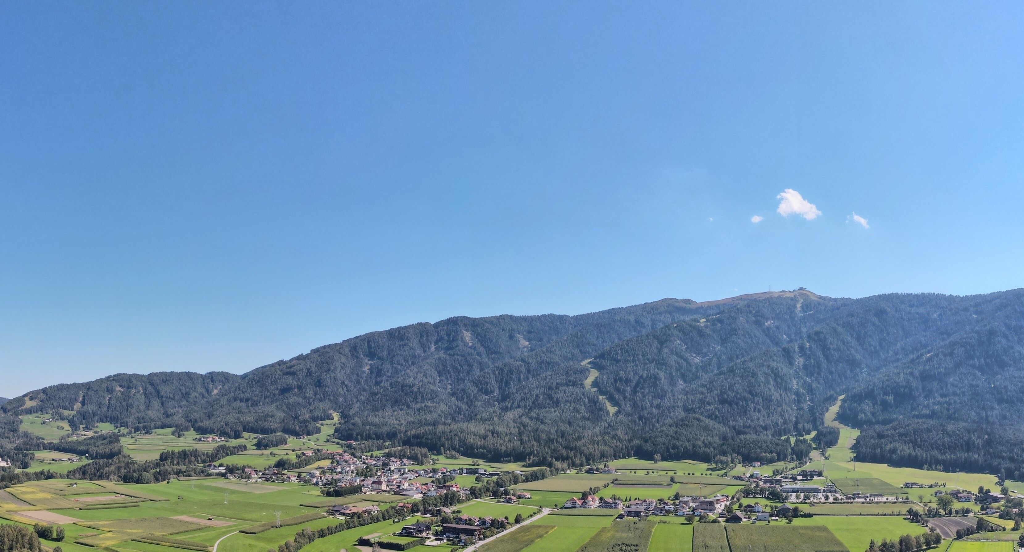 Et landligt landskab med en landsby placeret i dalen, omgivet af bjerge.