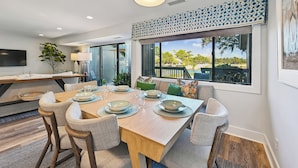 A modern dining area with a wooden table set for four, surrounded by wicker chairs. - Radiant Villa w/ Balcony, Deck & Amenities (Hilton Head Island)