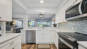 A modern kitchen with white cabinetry, a built-in microwave, and a dishwasher. - Radiant Villa w/ Balcony, Deck & Amenities (Hilton Head Island)