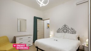 Et soveværelse med seng, sengebord, lampe, garderobe, spejl og en stol.
