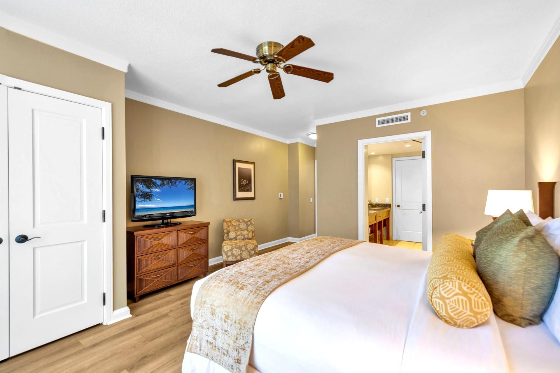 Ein Hotelzimmer mit Bett, Fernseher, einem Holzschrank und Deckenventilator.