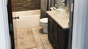 A modern bathroom with a bathtub, toilet, and vanity. - House for Rent- EAA  (Oshkosh)