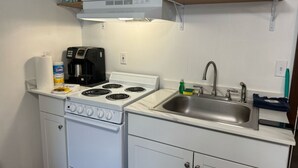 A compact kitchenette with a white stove, a sink, and a microwave. - Clean & Quiet Studio Apartment B (Nome)