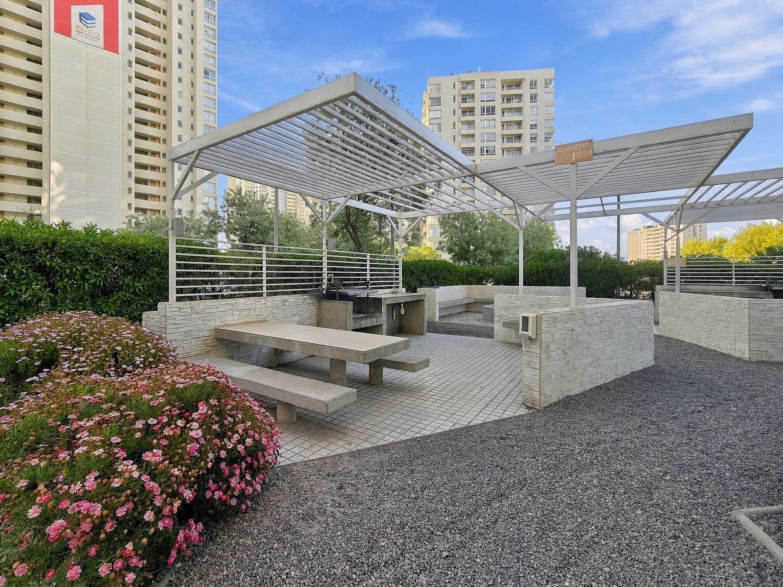 Ein Außenbereich mit Terrassengestaltung, einer Pergola, Sitzgelegenheiten und einem Blumenbeet.