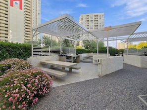 Un espace extérieur aménagé en patio, doté d’une pergola, de sièges et d’un parterre de fleurs.