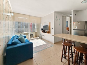 Una cocina moderna con refrigerador integrado, un comedor con taburetes y una sala de estar con sofá.