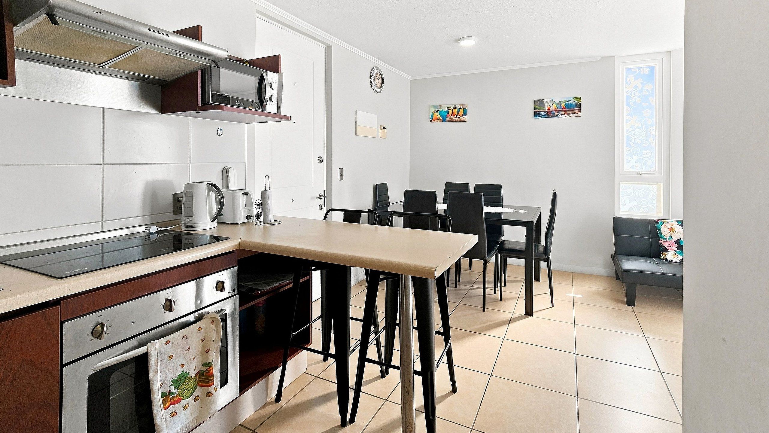 Eine moderne Küche mit Essbereich, ausgestattet mit Backofen, Kaffeemaschine und einem Esstisch mit Stühlen.