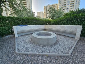 Una jardinera de hormigón circular rodeada de un banco de piedra en un espacio exterior.