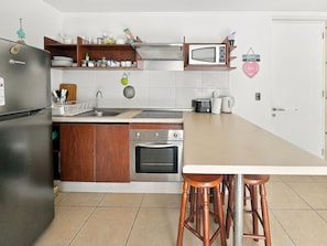 Une cuisine équipée d’un réfrigérateur, d’une cuisinière, d’un four à micro-ondes et de tabourets de bar.