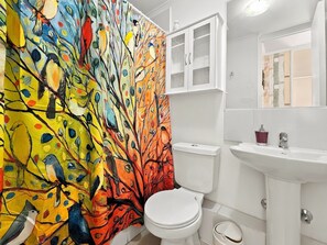 Une salle de bain avec des toilettes blanches, un lavabo blanc et un meuble au-dessus du lavabo.