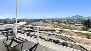 A high vantage point view of a parking area with multiple levels, a road, and distant cityscape.