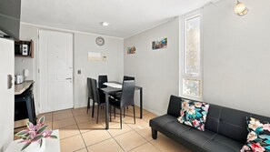 A compact living space with a dining area, a sofa, and a small kitchen area.