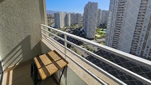 Ein Balkon mit Blick auf hohe Gebäude, einem kleinen Tisch und einem weißen Geländer.