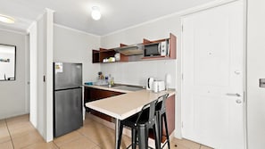 Una cocina compacta con refrigerador, microondas y una pequeña encimera.