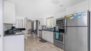 Una cocina moderna con armarios blancos, electrodomésticos de acero inoxidable y piso de baldosas.