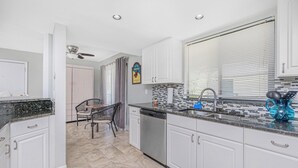 Una cocina moderna con armarios blancos, encimera negra y salpicadero de azulejos.