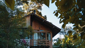 Une maison en bois dotée d’un balcon, entourée de verdure et bordée d’un chemin pavé.