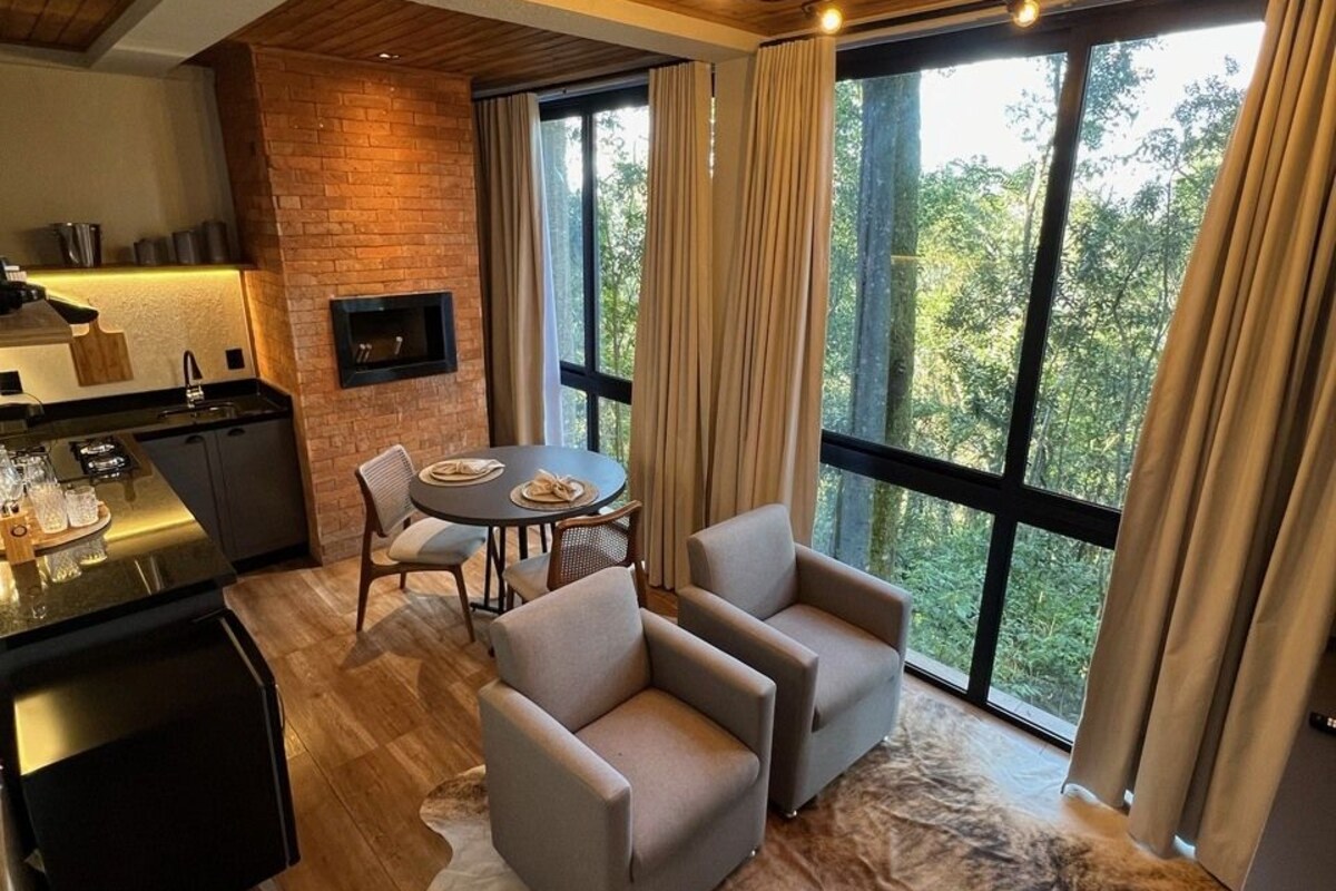 A modern kitchen with a brick accent wall, a dining area with two chairs, and a large window with curtains.