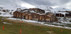 Un hôtel à plusieurs étages, doté d’une façade en bois, situé dans une région montagneuse, avec des sommets enneigés en toile de fond.