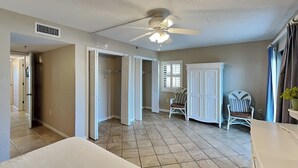 A bedroom with a bed, a ceiling fan, a wardrobe, and a chair. - Ocean Breeze West #106 | Gulf-Front, Ground Floor, Pool, Beach Access (Perdido Key)