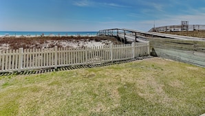 A beach with a wooden boardwalk, a white picket fence, and a clear blue sky. - Ocean Breeze West #106 | Gulf-Front, Ground Floor, Pool, Beach Access (Perdido Key)