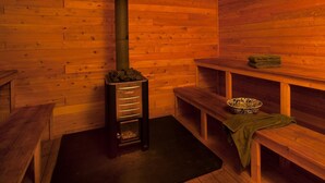Un sauna avec des murs en bois, un chauffage central, des bancs et une étagère avec des serviettes.