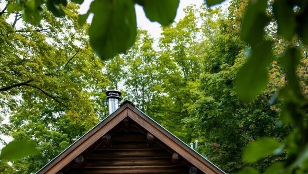Une cabane en bois rustique, dotée d’un porche, d’une enseigne indiquant « White Cap » et d’une pile de bois de chauffage.