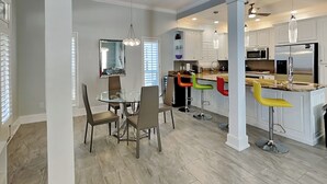 Una cocina moderna con armarios blancos, electrodomésticos de acero inoxidable y una isla central con taburetes de bar.