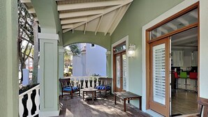 Un área de estar al aire libre con techo, muebles de madera y vista a la calle.