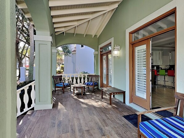 A covered outdoor seating area with wooden furniture and a view of the street.