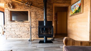 Una habitación acogedora con una pared de madera, una chimenea, un televisor y un cuadro.