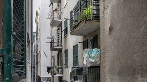 A narrow urban street with multi-story buildings, balconies with plants, and laundry hanging outside. - Casa Alma by Wonderful Italy (Genoa)