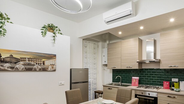 A modern kitchen with a built-in stove, sink, and a refrigerator. There is a dining area with a table and chairs. - Casa Alma by Wonderful Italy (Genoa)
