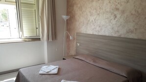 A neatly made bed with a brown bedspread and two folded white towels. - HOTEL HRS (Follonica)