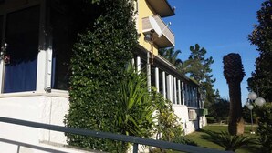 A building with a white facade, large windows, and a balcony with a metal railing. - HOTEL HRS (Follonica)
